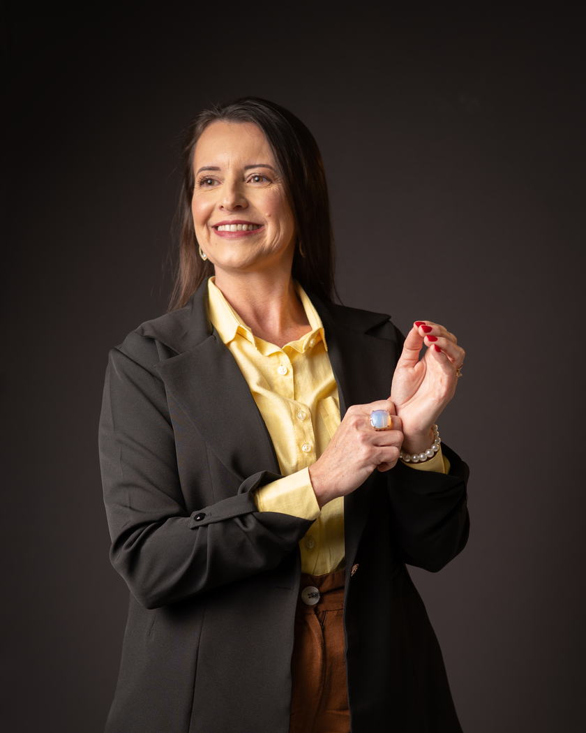 Marília Bernardes em pé, ajustando a manga do blazer